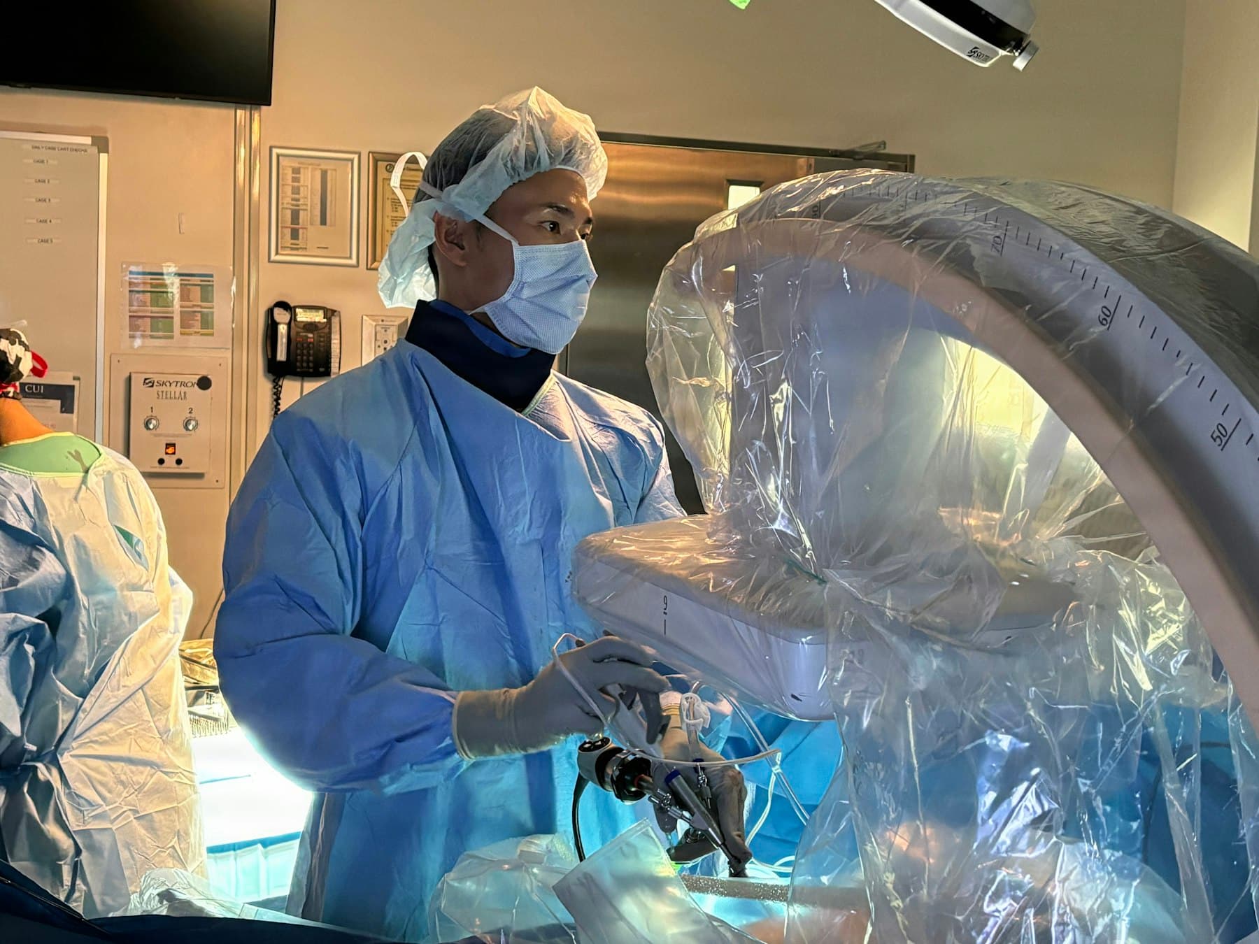 Surgeon in the operating room next to a draped robotic surgery system