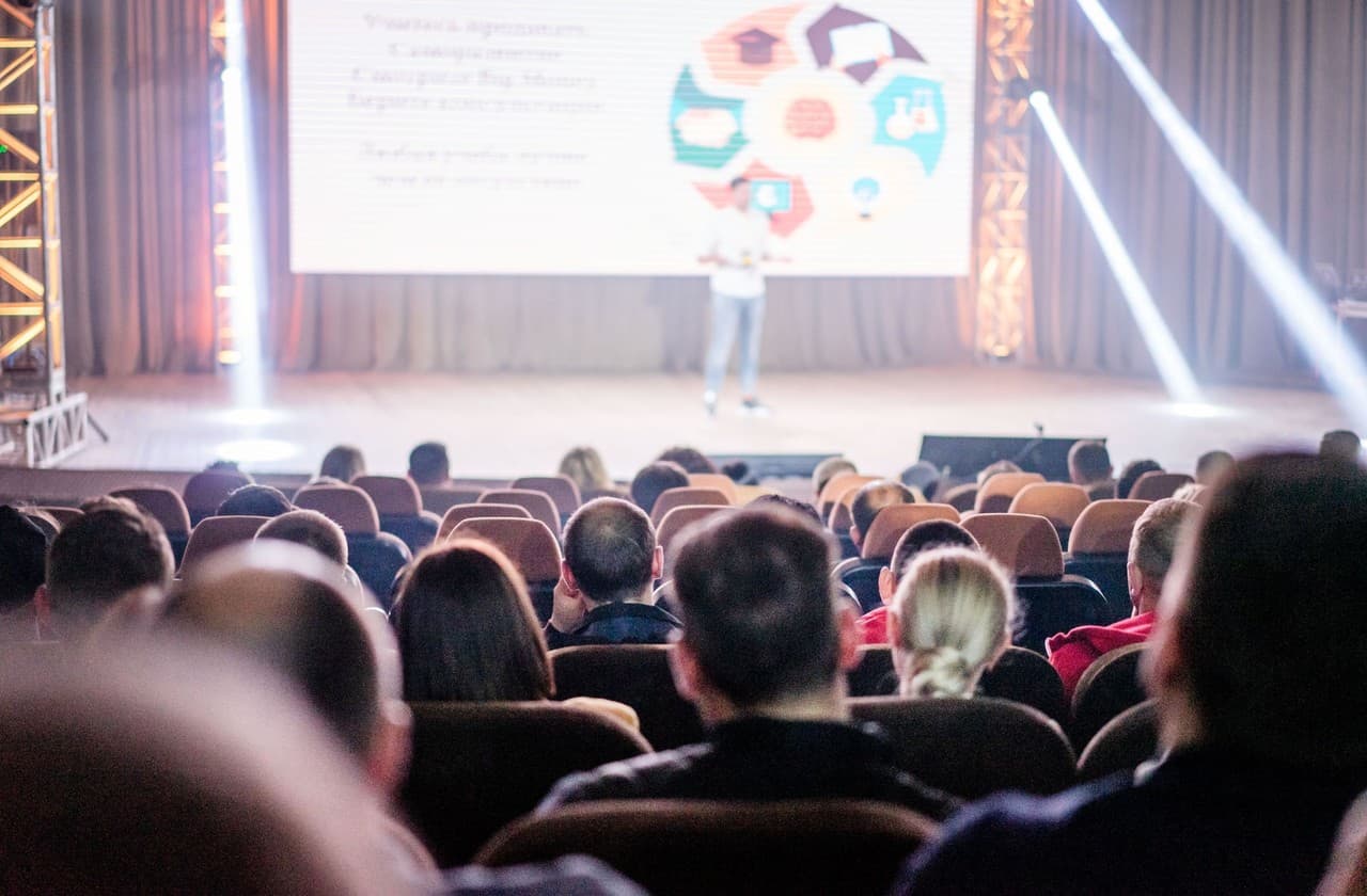 Audience in a congress hall facing a speaker on stage